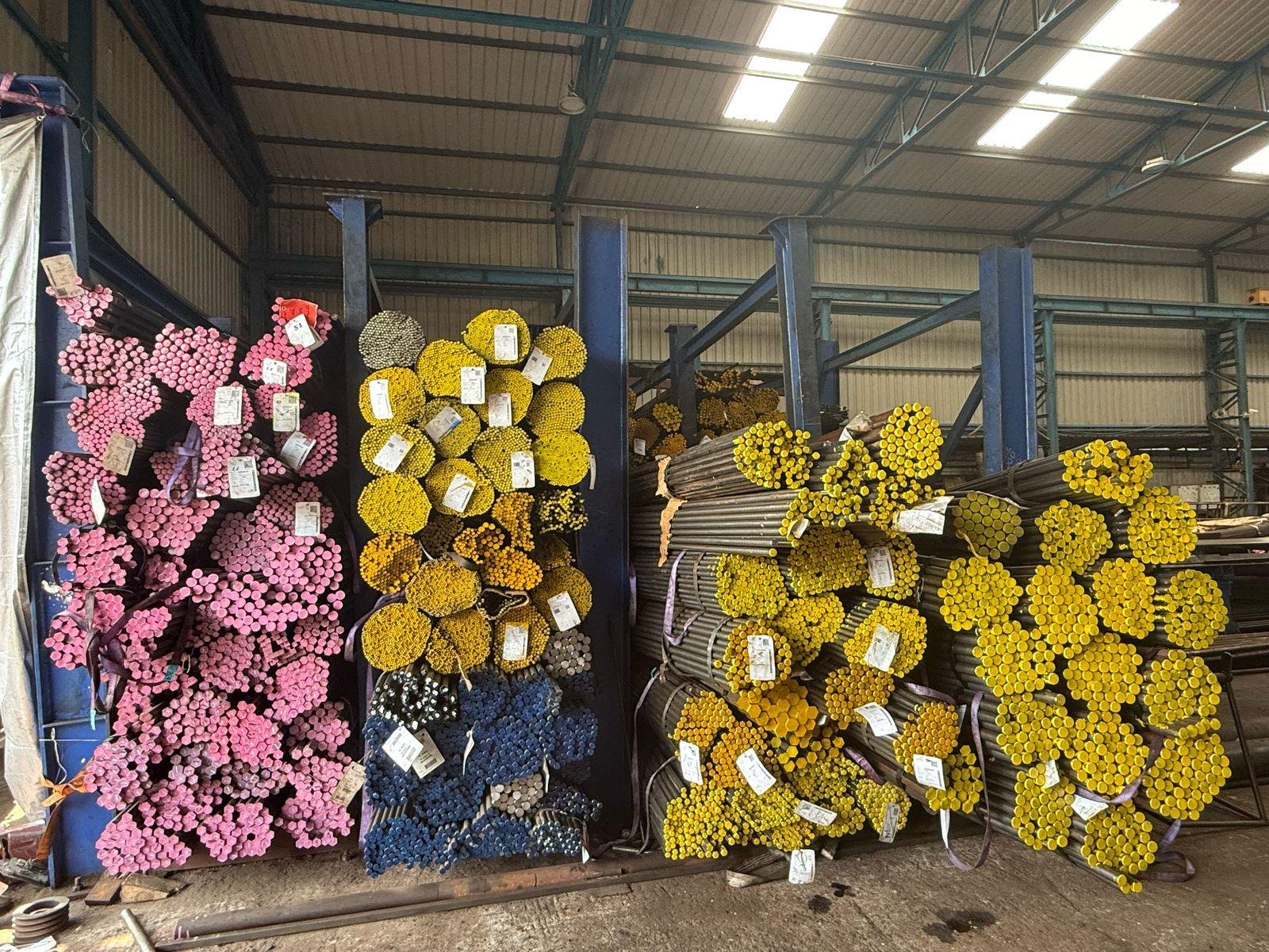 Colour-coded bright bar stock racked by grade at the Radhe Steel warehouse in Bhosari, Pune